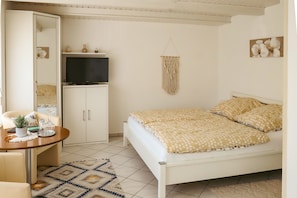 Une chambre à coucher comprenant un lit, un téléviseur, un bureau avec une chaise et un tapis à motifs.
