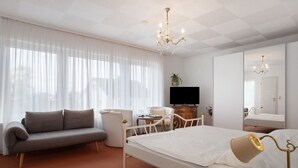 A hotel room with a bed, a sofa, a TV, a bedside table, and a mirror. - Room 'Doppelzimmer 7' with Balcony and Wi-Fi (Wasserburg (Bodensee))