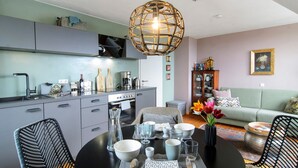 A modern kitchen with grey cabinets, a dining table set with bowls and glasses, and a hanging light fixture. - Apartment 'Gute Nacht In Der Acht' with Lake View, Private Garden and Wi-Fi (Überlingen)