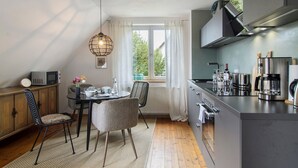 A modern kitchen with a dining area, a microwave, a coffee maker, and a view of greenery outside. - Apartment 'Gute Nacht In Der Acht' with Lake View, Private Garden and Wi-Fi (Überlingen)