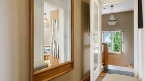 A hallway with a mirror, a door leading to a bedroom, a window with a view, and a chandelier. - Apartment 'Gute Nacht In Der Acht' with Lake View, Private Garden and Wi-Fi (Überlingen)