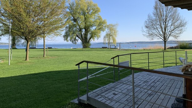 A deck with a railing overlooking a grassy area with trees and a body of water in the background. - Apartment 'Gute Nacht In Der Acht' with Lake View, Private Garden and Wi-Fi (Überlingen)