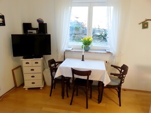 Zona pranzo con tavolo, sedie, televisore e finestra vista esterna.