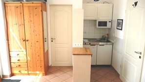 A kitchen with white cabinets, a microwave, and a wooden door.