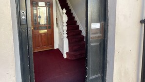A staircase leading to an upper floor, with a red carpeted landing and a wooden door at the top. - Victoria Inn (Alston)
