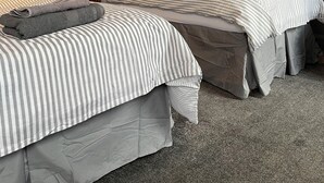 A hotel room with two beds, grey walls, and a carpeted floor. - Victoria Inn (Alston)