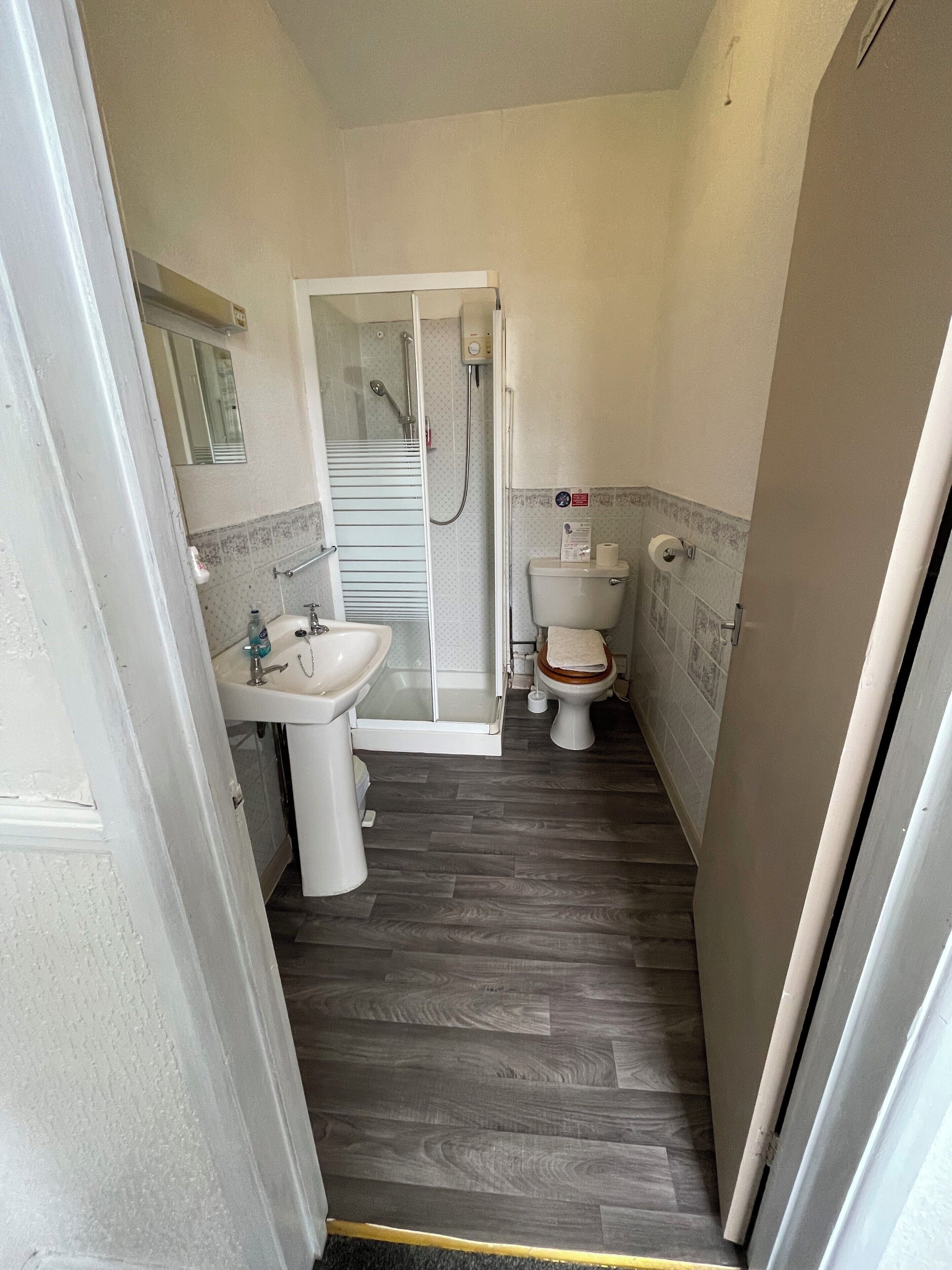 Et lille badeværelse med bruser, toilet og håndvask.