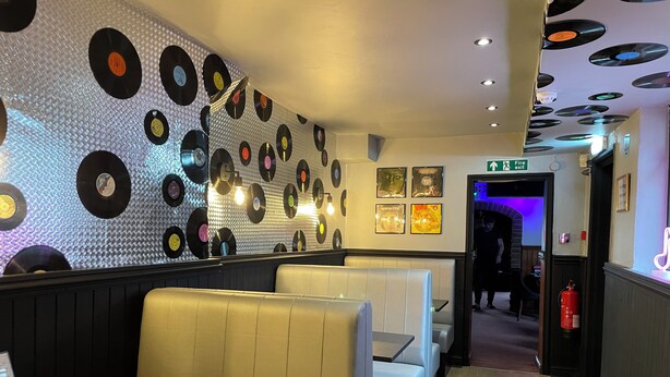 A restaurant interior with vinyl record wall decor, booths, and a fire exit sign. - Victoria Inn (Alston)
