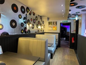 En restaurantindretning med vægdekoration bestående af vinylplader, båse og skilt med brandudgang.