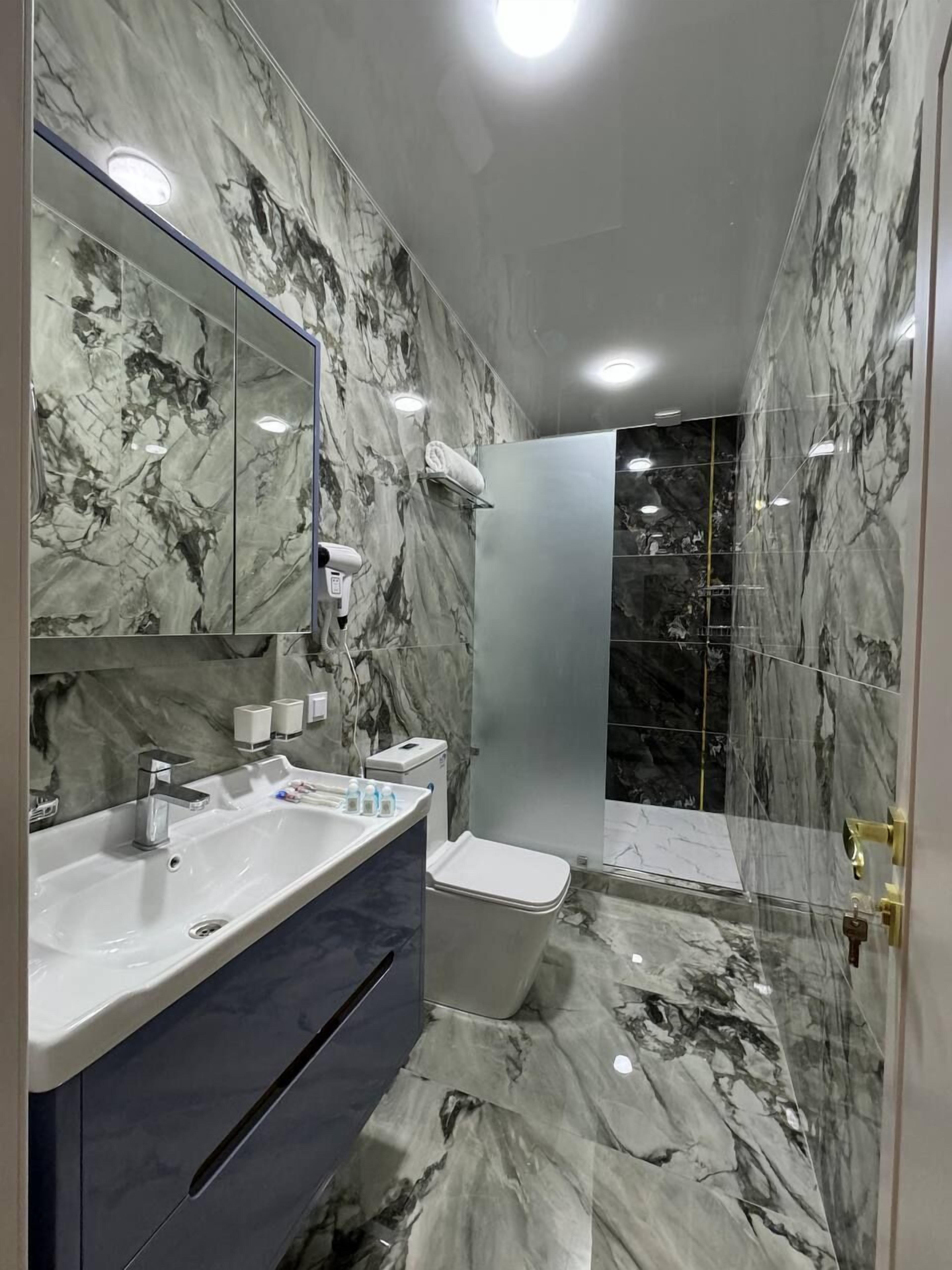 A bathroom with marble walls, a modern sink, and a shower area.