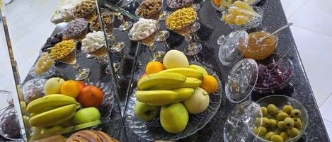 A buffet with various food items including fruits, nuts, and pastries.