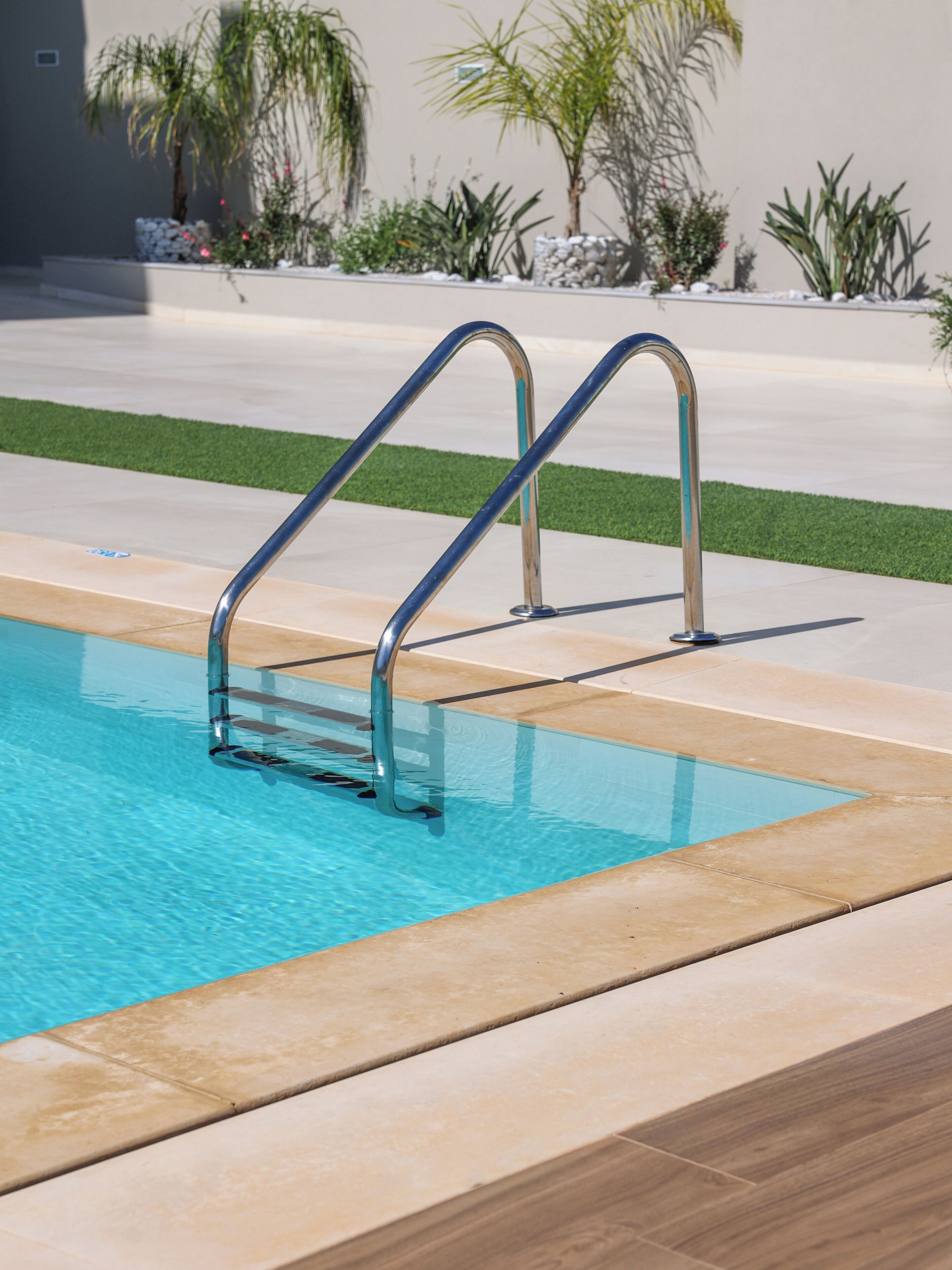 A swimming pool with metal handrails and a tiled deck.