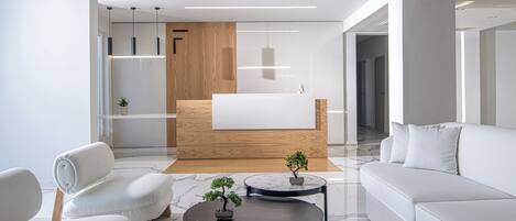 A modern living room with a white sofa, a black coffee table, and a wooden reception desk.