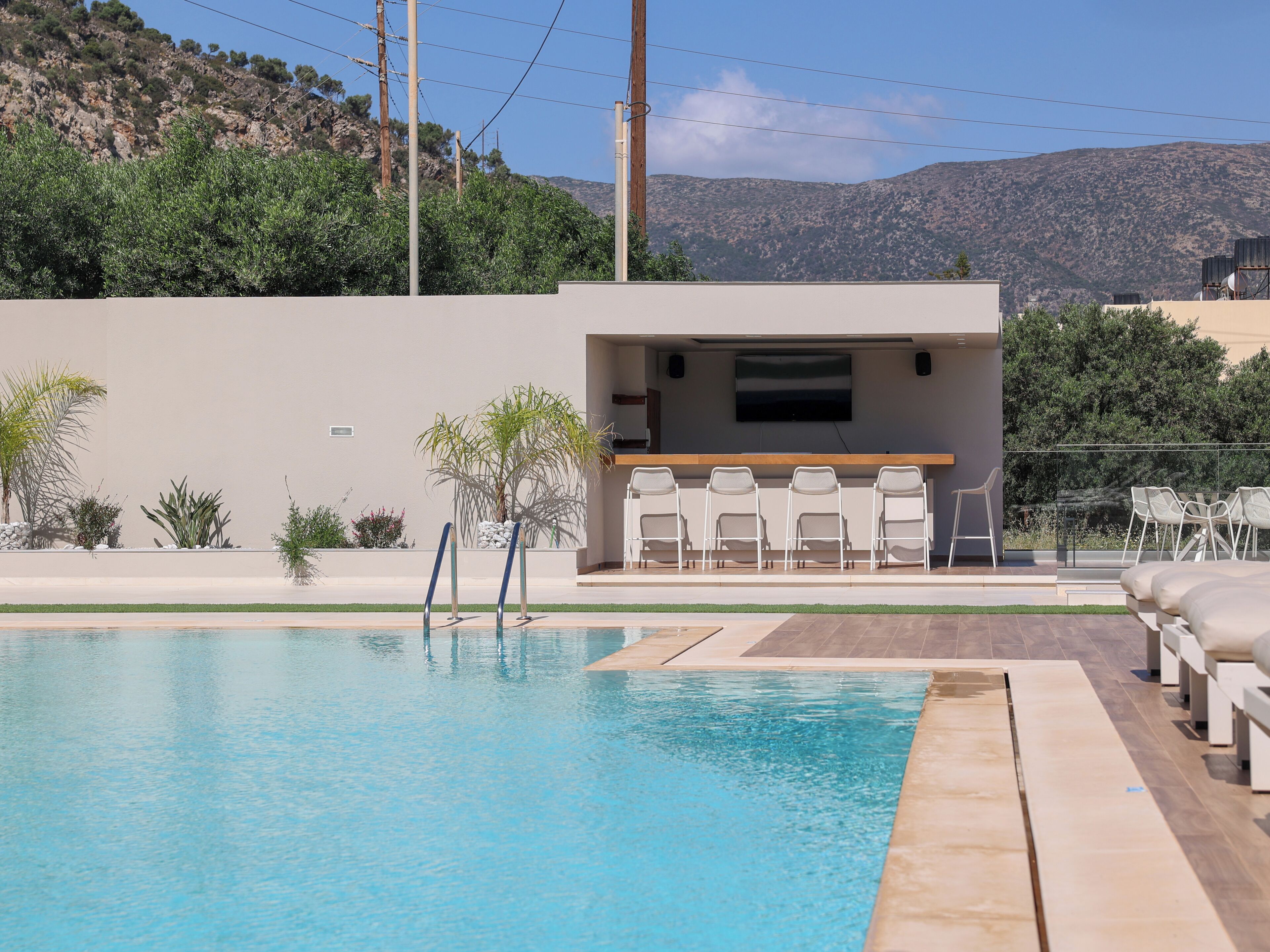 A swimming pool with a bar area, chairs, and a view of mountains.