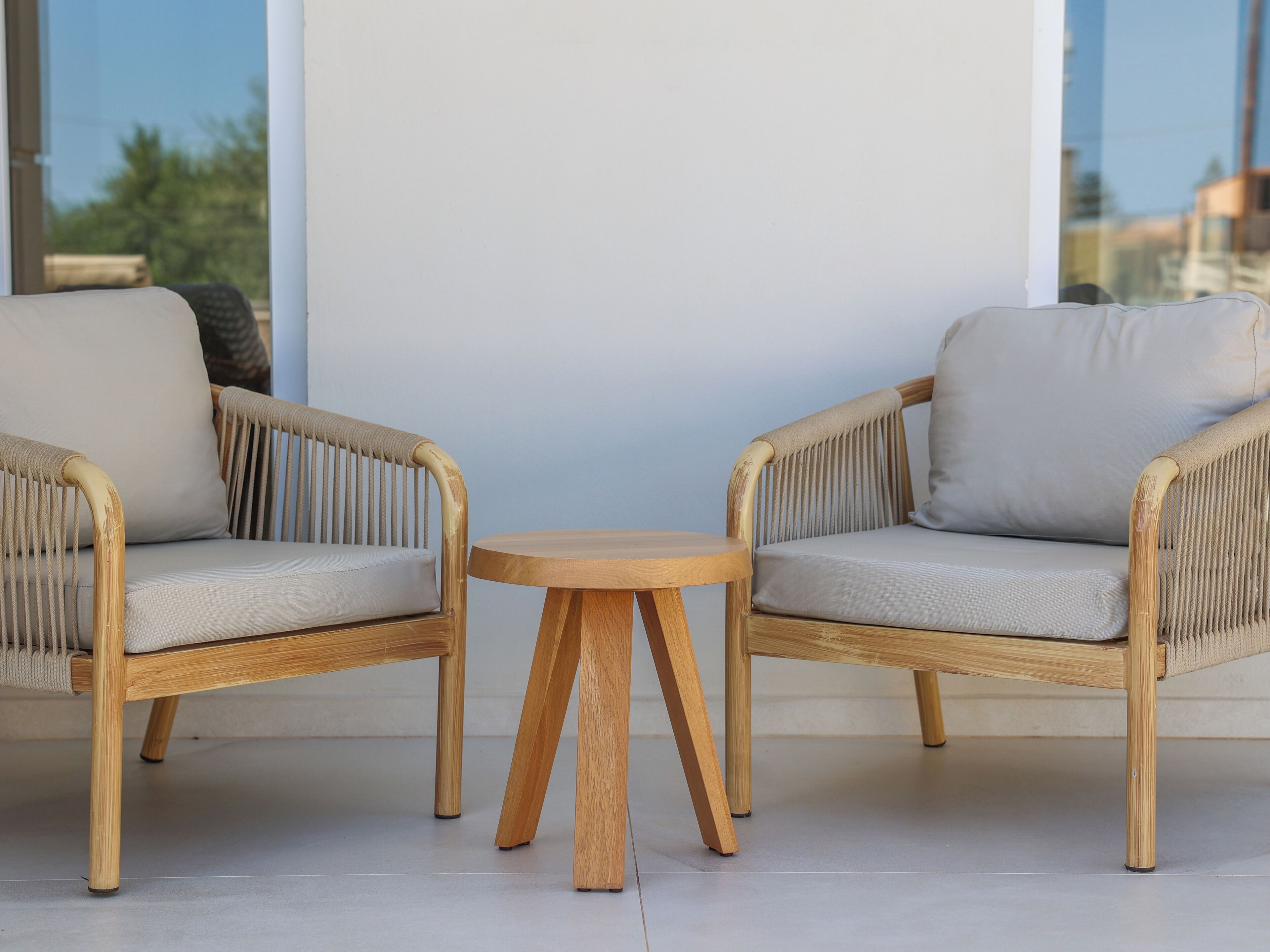 Two wicker chairs with cushions, a small wooden table, and a view through a window.