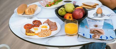 A breakfast table with plates of eggs, beans, toast, and fruit.