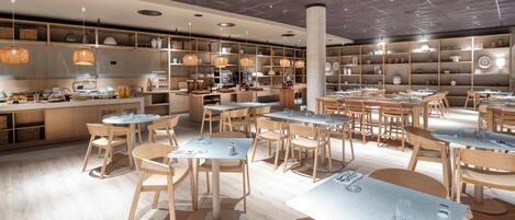 Un restaurante moderno con mobiliario de madera, mesas redondas y lámparas colgantes.