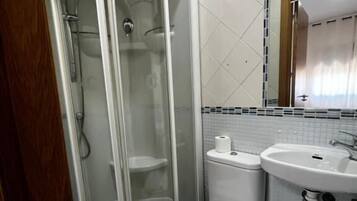 Un baño con ducha de vidrio, inodoro, lavabo y espejo.