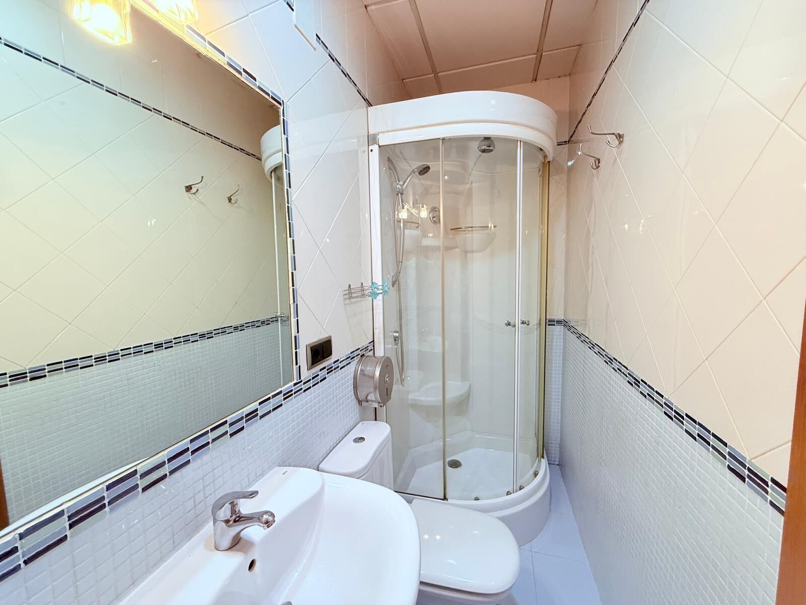 Un baño con ducha de vidrio, lavamanos e inodoro.