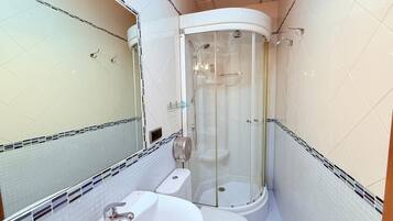 Ein Badezimmer mit einer Duschkabine, einem Waschbecken und einer Toilette.