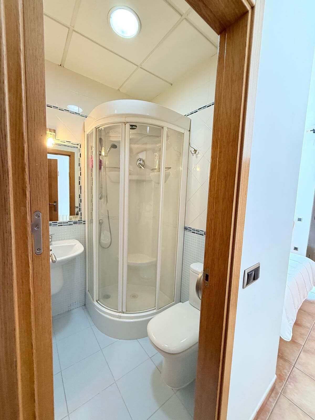 Et lille badeværelse med en brusekabine i glas, toilet og håndvask.