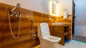 A modern bathroom with a wooden wall, a white toilet, a sink, and a shower. - Falcon'S Cottages (Leh)