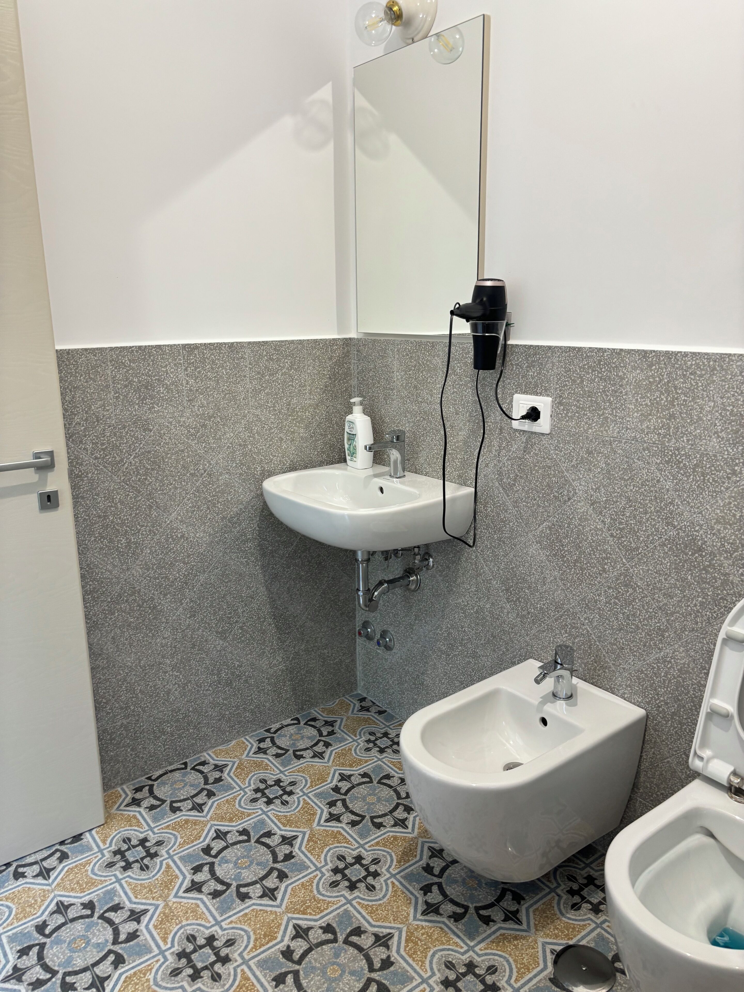 A bathroom with a white sink, bidet, and a mirror.