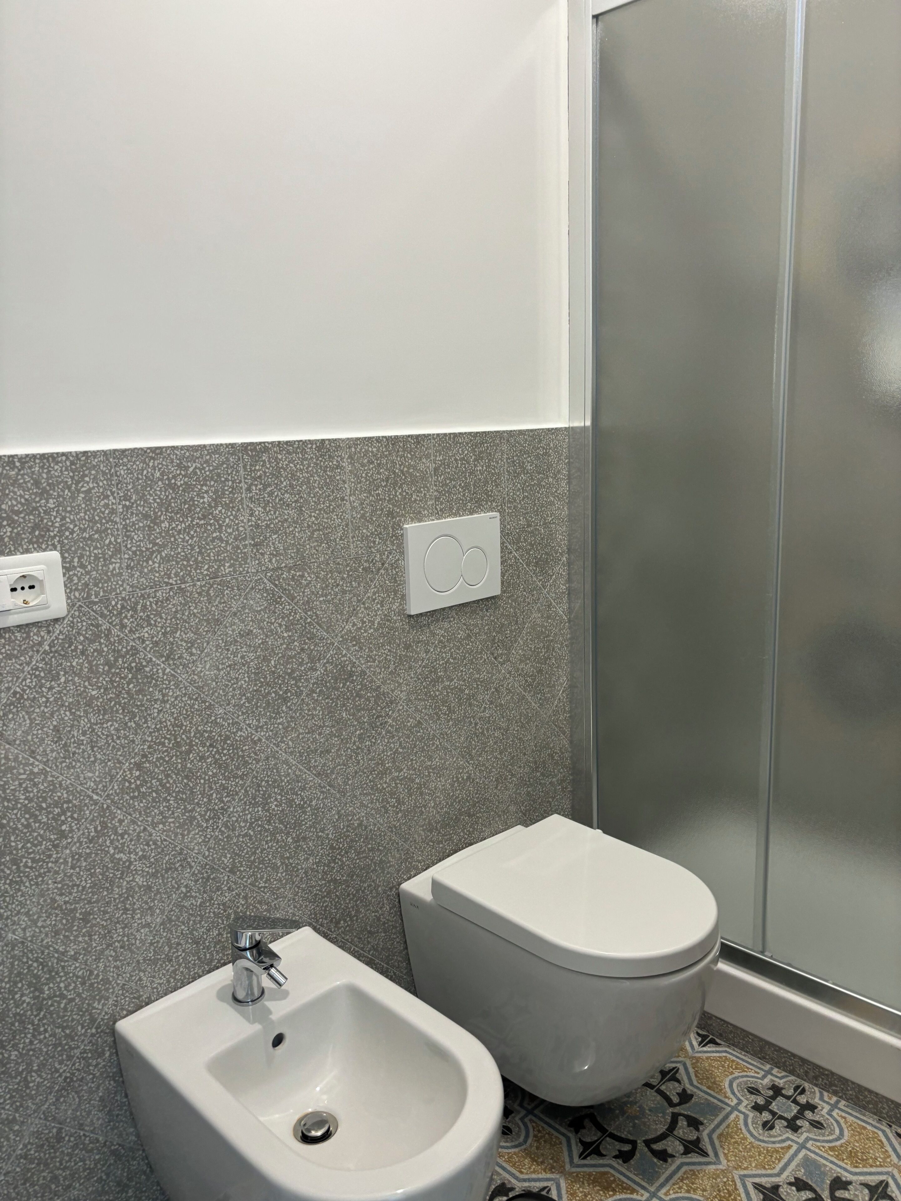 A bathroom with a bidet, toilet, and a shower area.