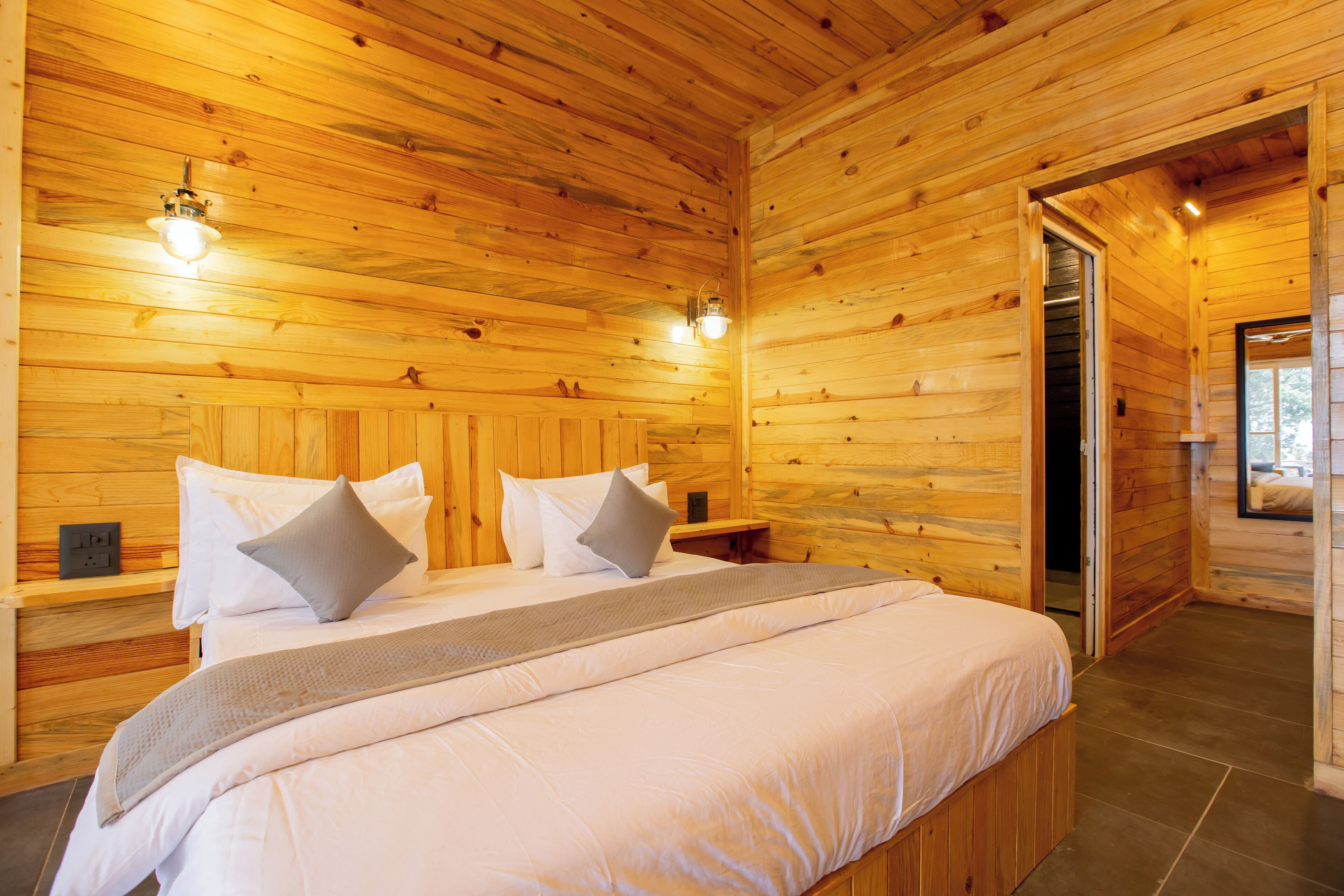 A wooden cabin bedroom with a bed, pillows, and a nightstand.
