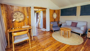 Una habitación acogedora con piso de madera, un sofá, una silla, una mesita y una lámpara.