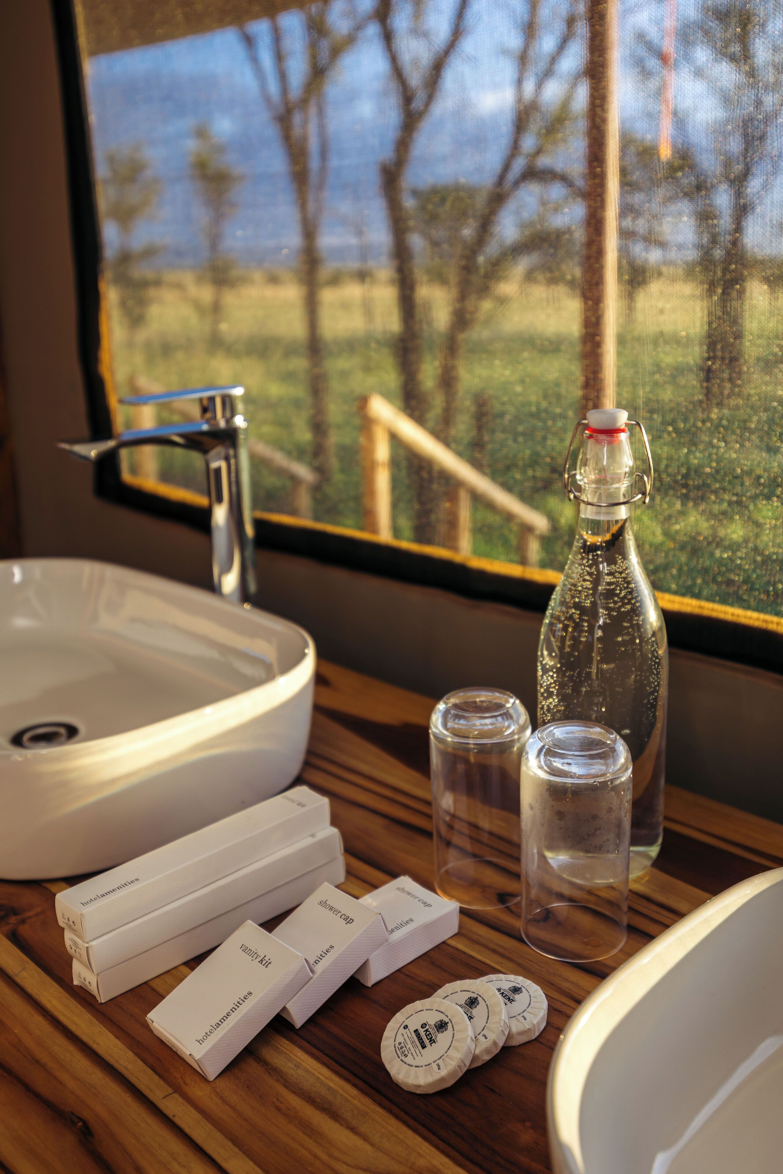 A bathroom with a sink, a bottle, and toiletries on a wooden counter.