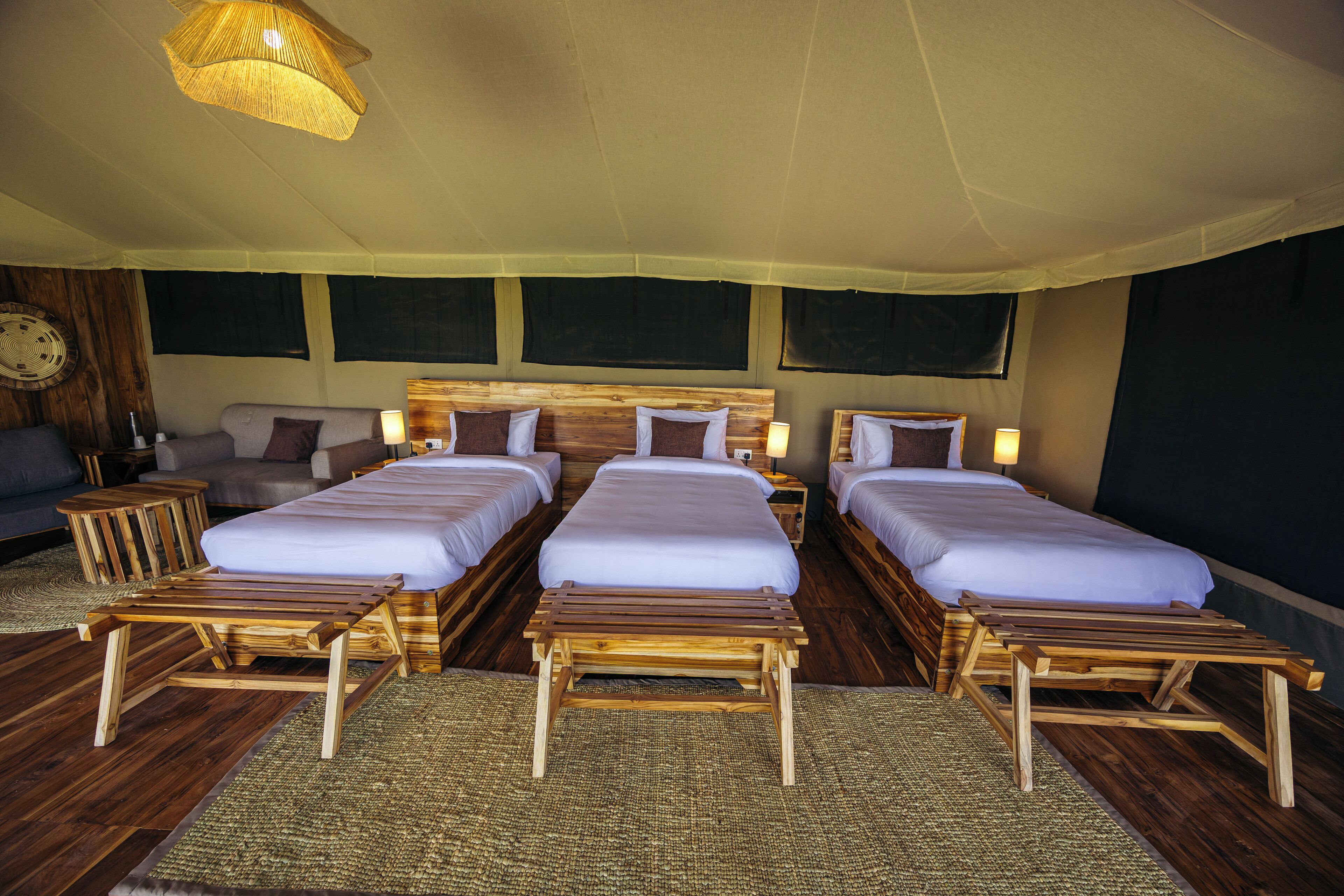 A hotel room with three beds, wooden headboards, and a large bed at the center.