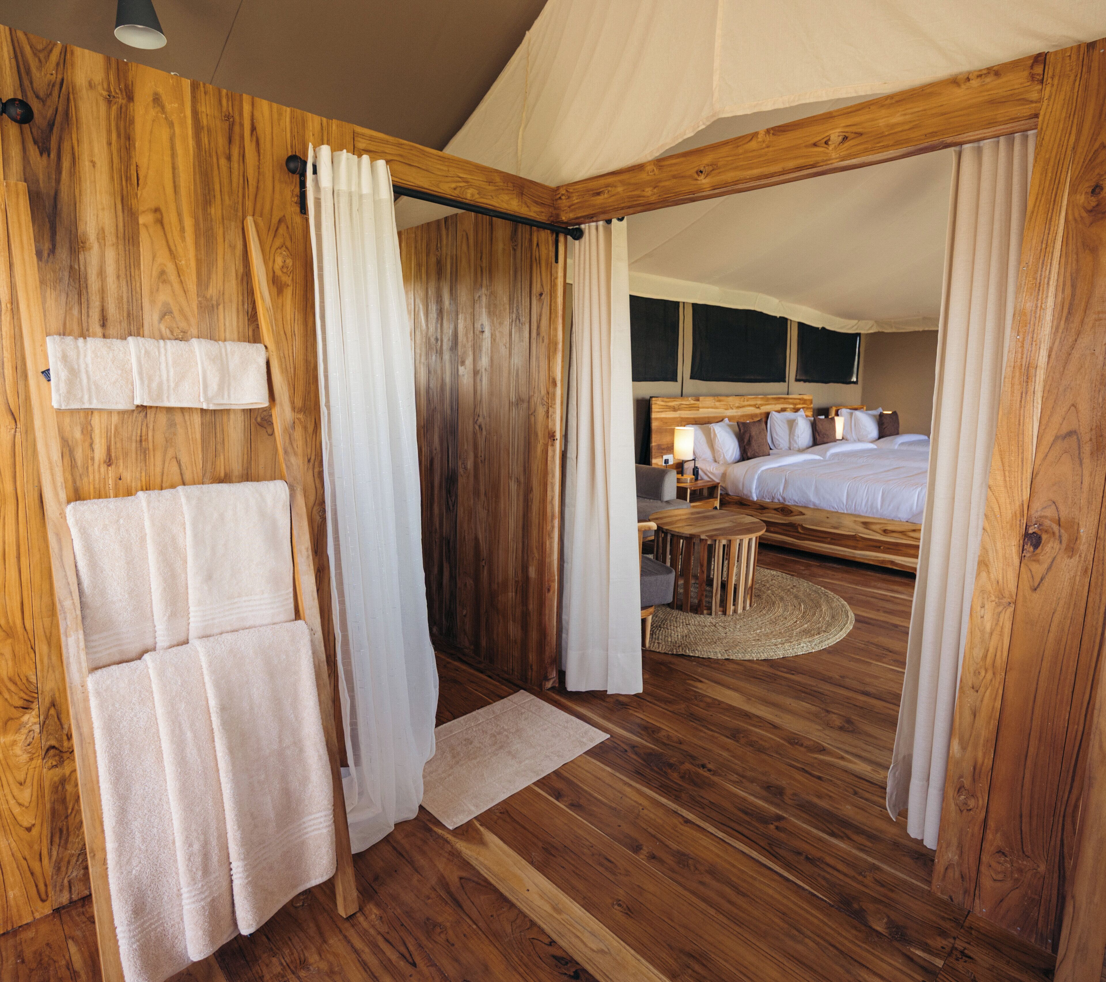 Una habitación de madera con una cama, una mesita y una silla.
