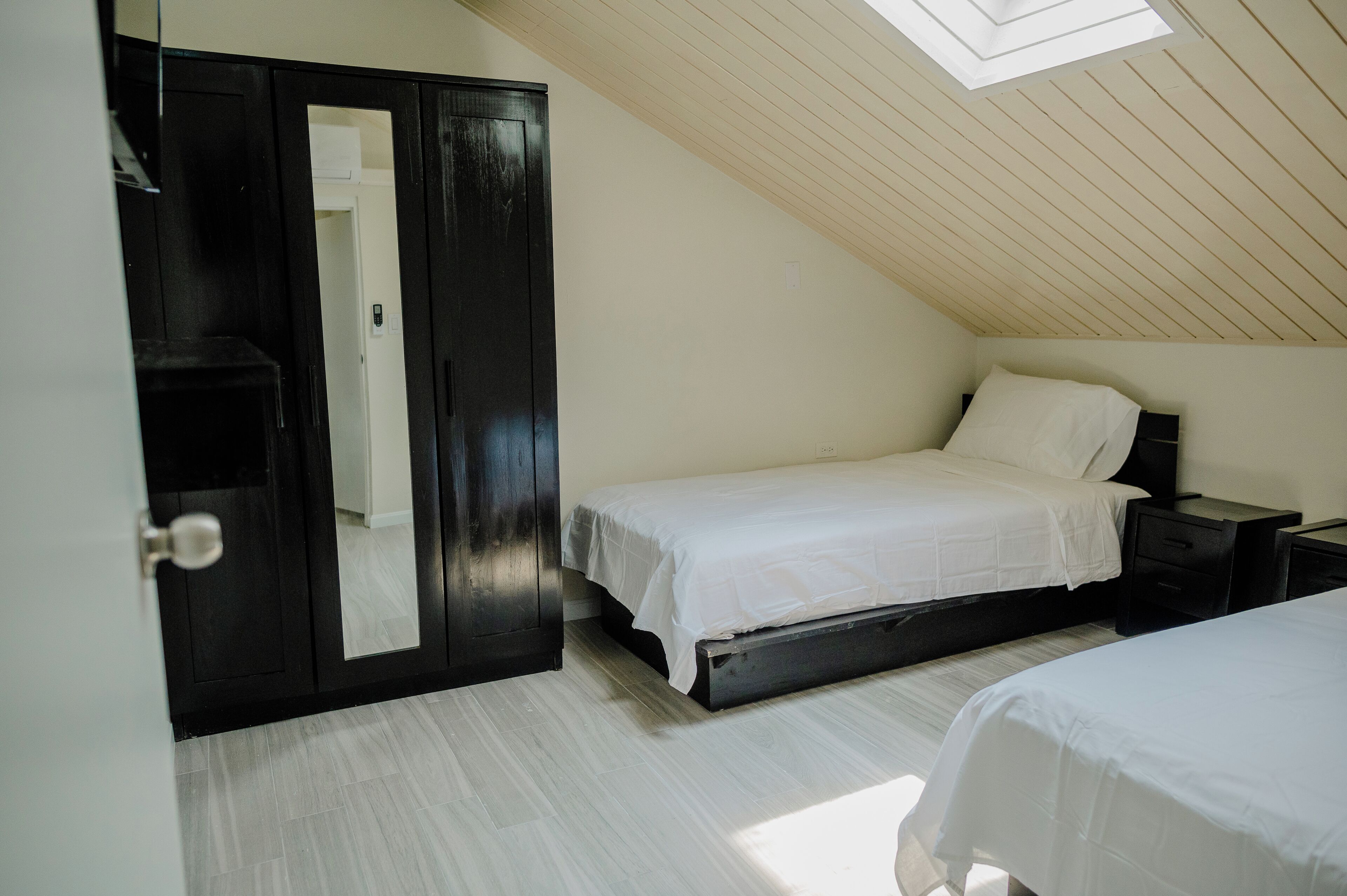 Une chambre avec un puits de lumière, une armoire et un lit.