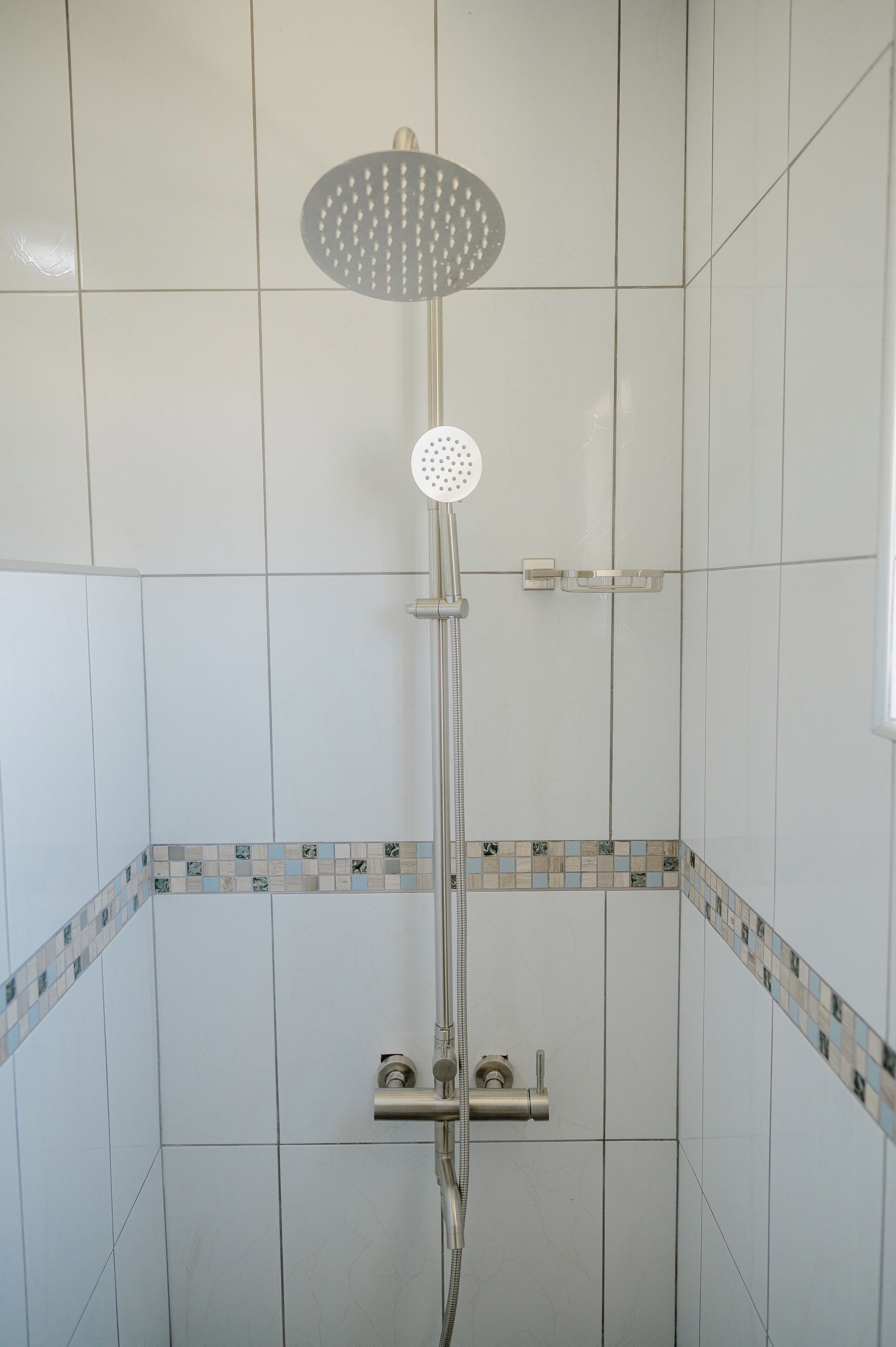 Ducha con cabezal de ducha de mano y grifo empotrado.