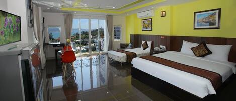 A hotel room with two beds, a balcony with a view, a dining area, and a TV.