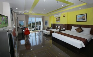 A hotel room with two beds, a balcony with a view, a dining area, and a TV.