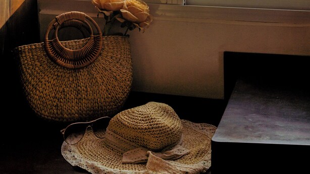 A view of the ocean through a window, with a wicker basket and a straw hat on a table beside the window. - Melyna Hotel Nha Trang Beach (Nha Trang)