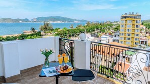 A balcony with a table set for breakfast, overlooking a coastal cityscape. - Melyna Hotel Nha Trang Beach (Nha Trang)