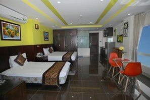 A hotel room with two beds, a kitchenette, and a dining area with red chairs. - Melyna Hotel Nha Trang Beach (Nha Trang)