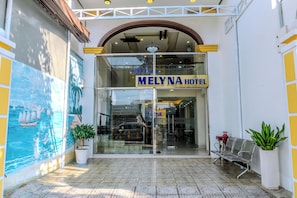 The entrance to Melyna Hotel with a clear glass facade, a mural on the left, and a bench outside. - Melyna Hotel Nha Trang Beach (Nha Trang)