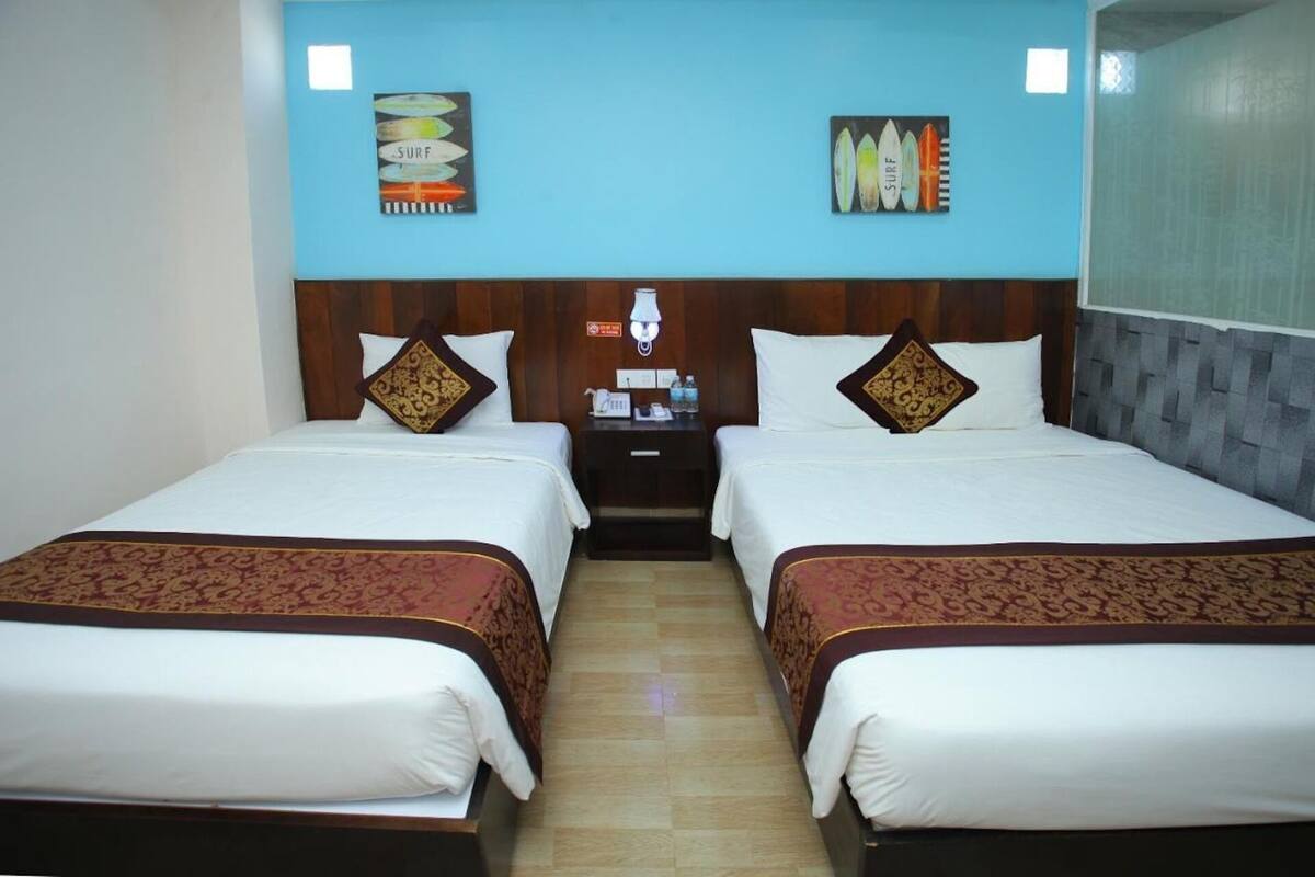 Une chambre d’hôtel avec deux lits, une table de chevet avec une lampe et des œuvres d’art accrochées aux murs.
