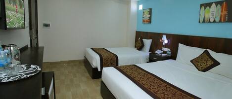 A hotel room with two beds, a desk with a coffee maker, and a TV on the wall.