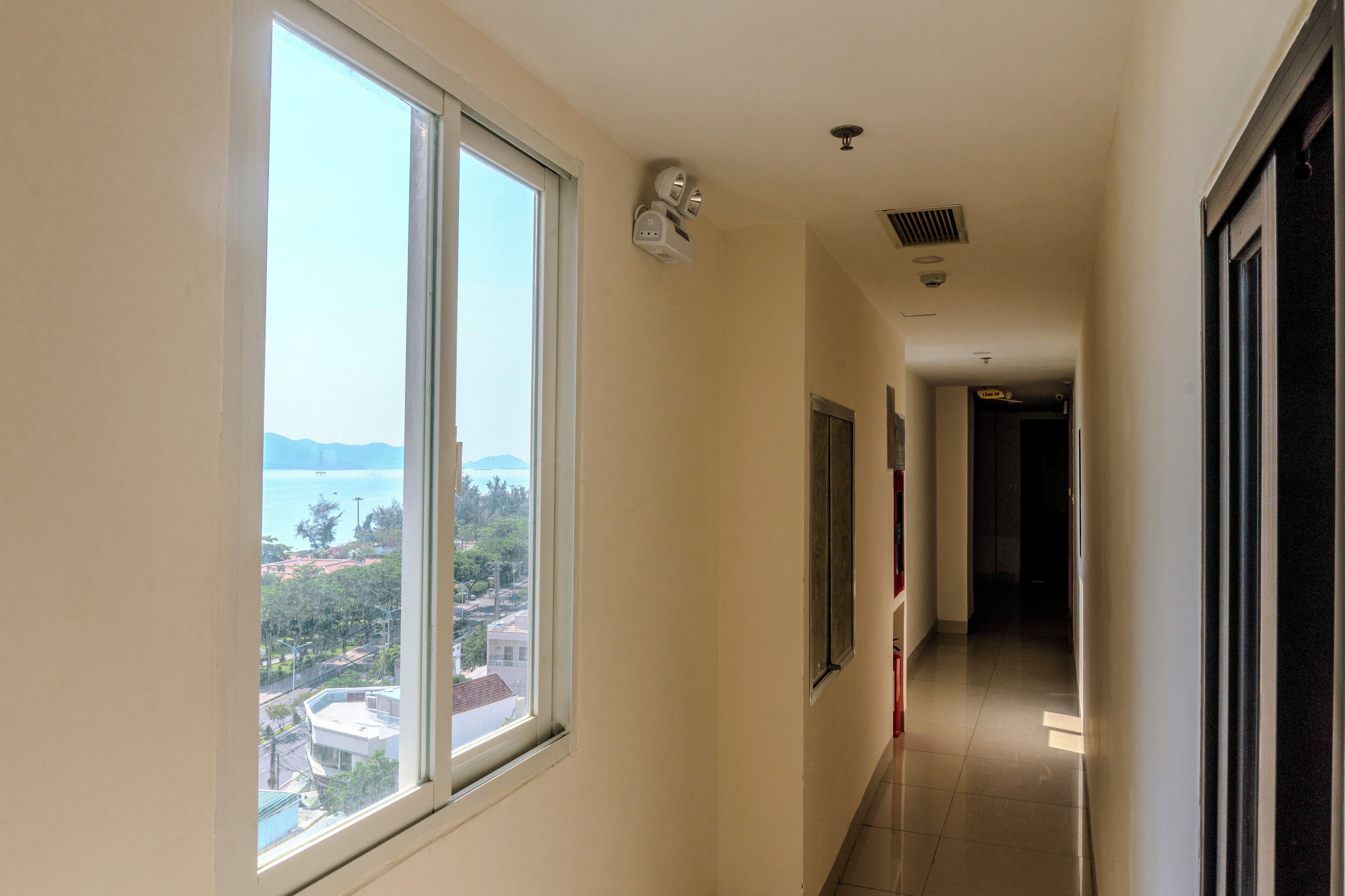 A corridor with a large window offering a view of a body of water and distant buildings.
