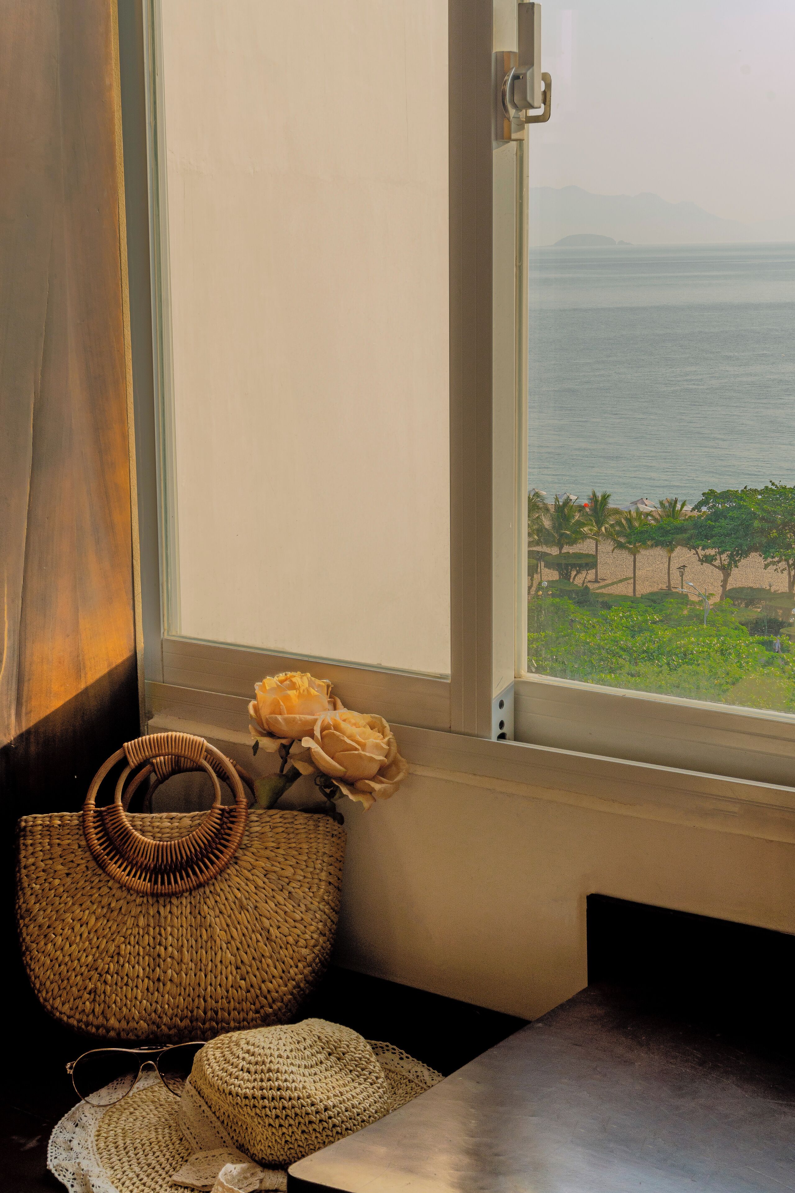 A room with a view of the ocean, a wicker basket, and a crocheted item on a table.