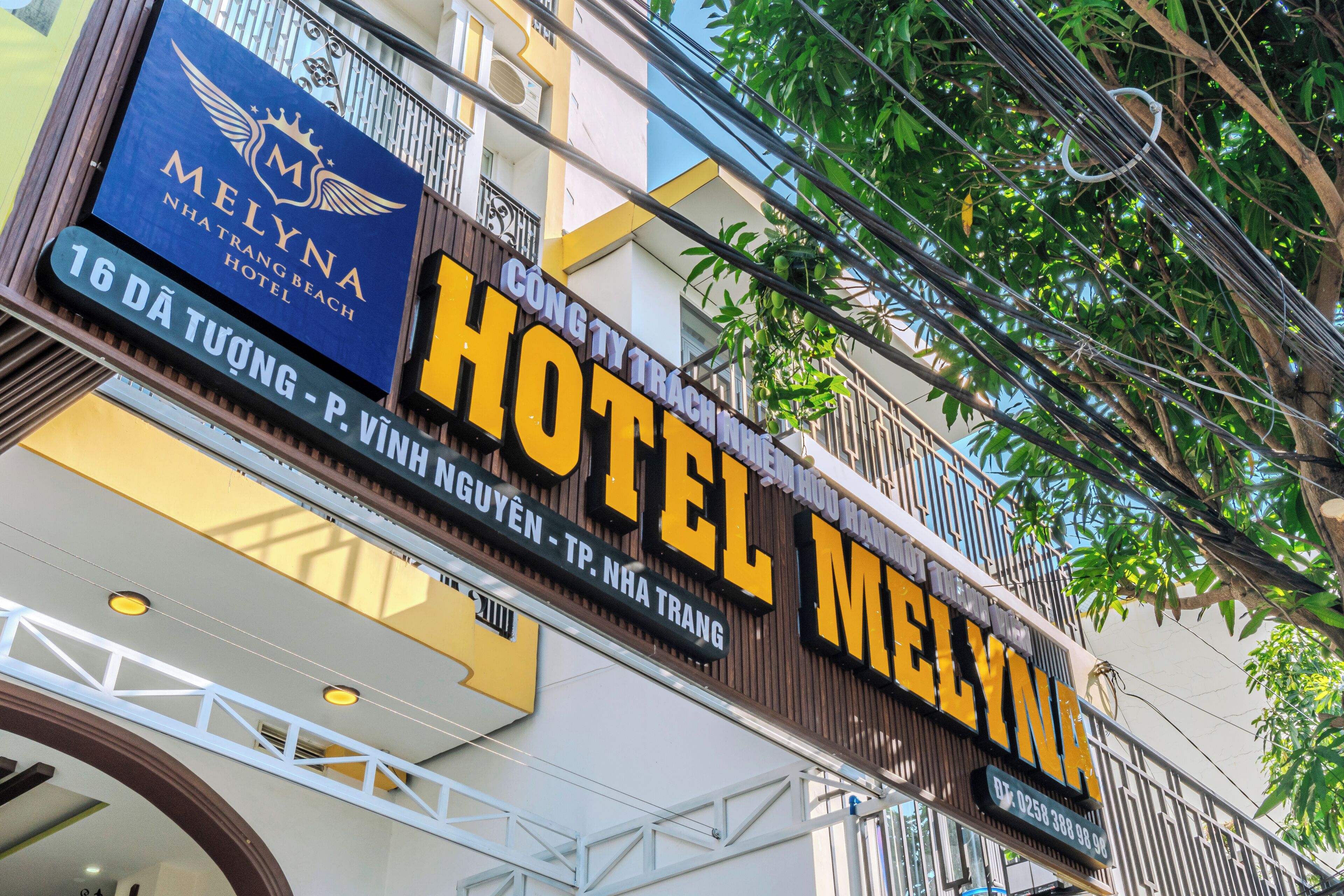 A hotel sign with the name "MELYNA HOTEL" and a smaller sign for "MELYNA NHA TRANG BEACH HOTEL".