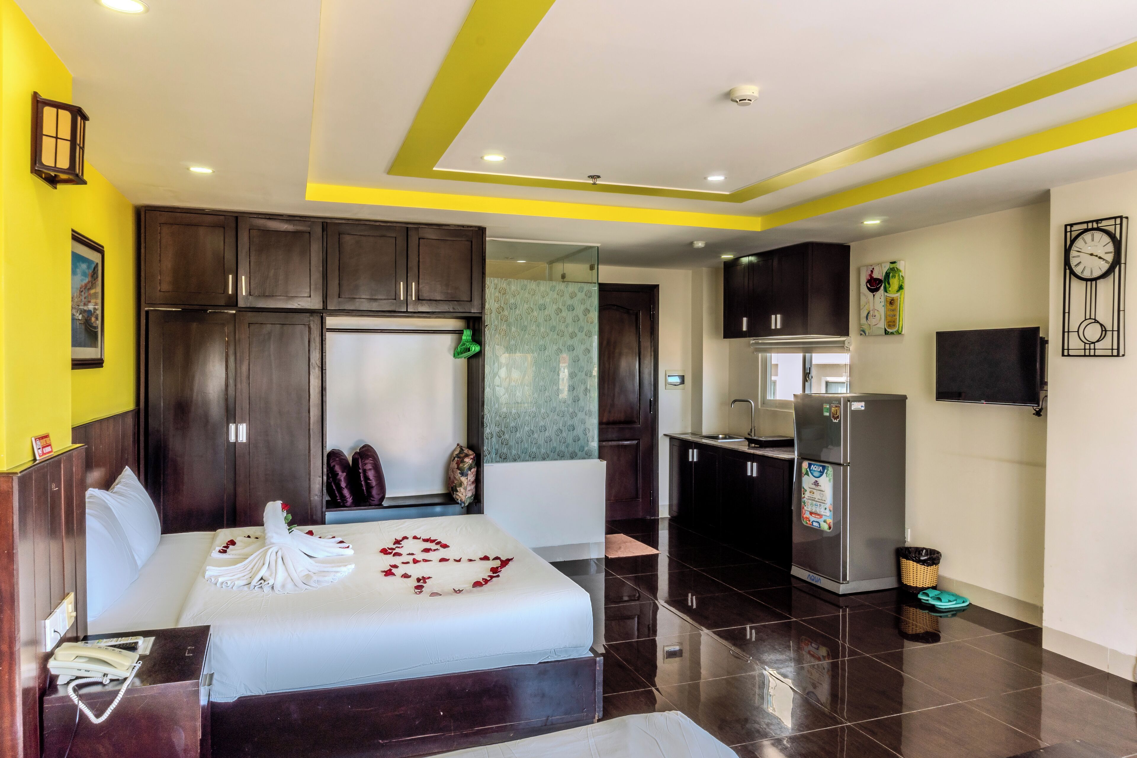 A hotel room with a bed, a desk, a wardrobe, a kitchenette, and a bathroom.