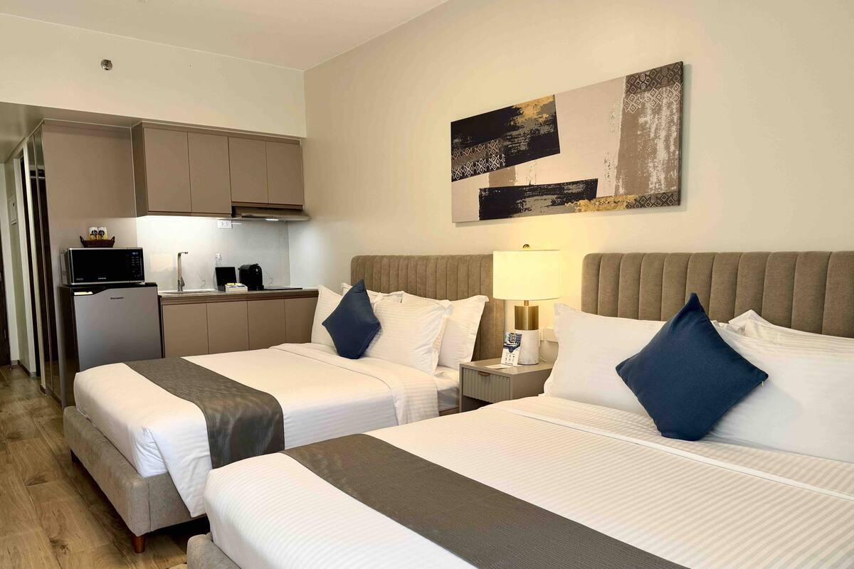 Habitación de hotel con dos camas, una kitchenette y un comedor.