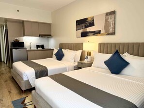Ein Hotelzimmer mit zwei Betten, einer Küchenzeile und einem Essbereich.