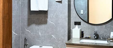 Un baño moderno con inodoro, lavamanos, espejo y toallero.